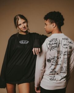 Young adults modeling edgy streetwear with bold text designs in a studio setting.