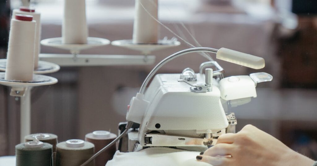 A person sewing fabric on a professional machine in a well-lit workshop with spools of thread.