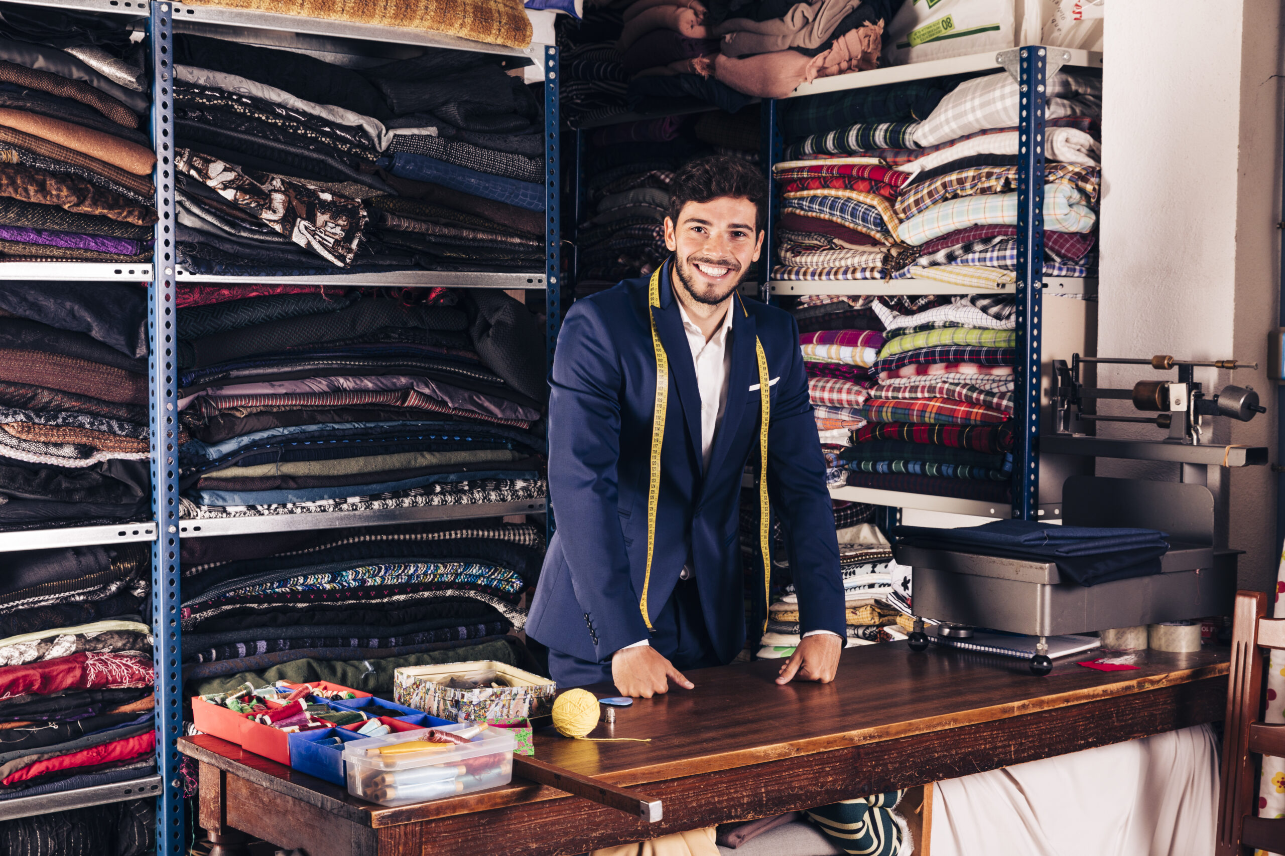 portrait smiling young male fashion designer looking camera his shop